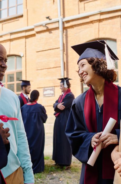 Parents congratulating their children with graduation of university while they standing outdoors