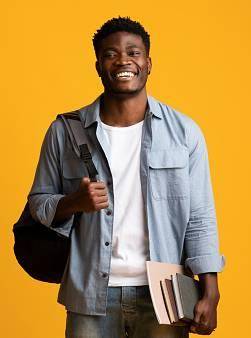 Positive millennial black man student in casual posing with books and notepads on yellow studio background, young african american guy enjoying studying at university or college, copy space